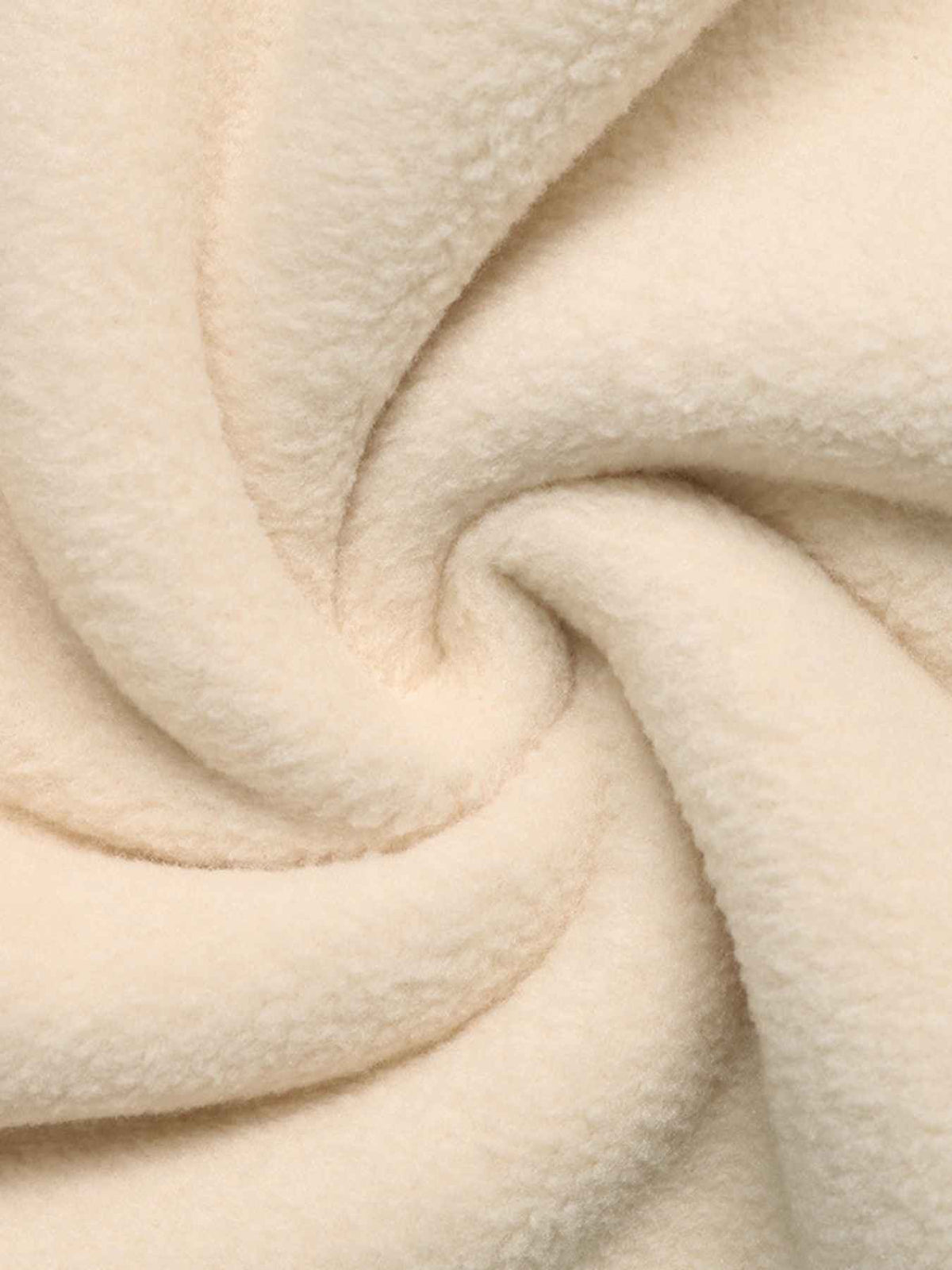 A close-up of a soft, plush fleece fabric in a warm cream or off-white color, arranged in a spiral drape to show its texture and folds.