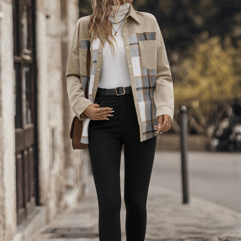 A woman stands on a city sidewalk wearing a beige patchwork button-up shirt jacket with plaid and white panels, layered over a white turtleneck, black skinny pants, and a brown shoulder bag.