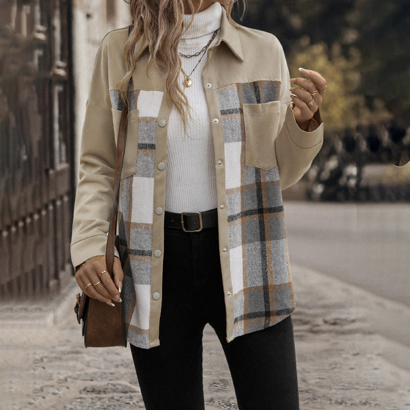 Person wearing a plaid shirt over a white turtleneck with a blurred background