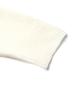 A close-up of a cream-colored ribbed knit fabric, showing the texture and folded cuff edge on a white background.