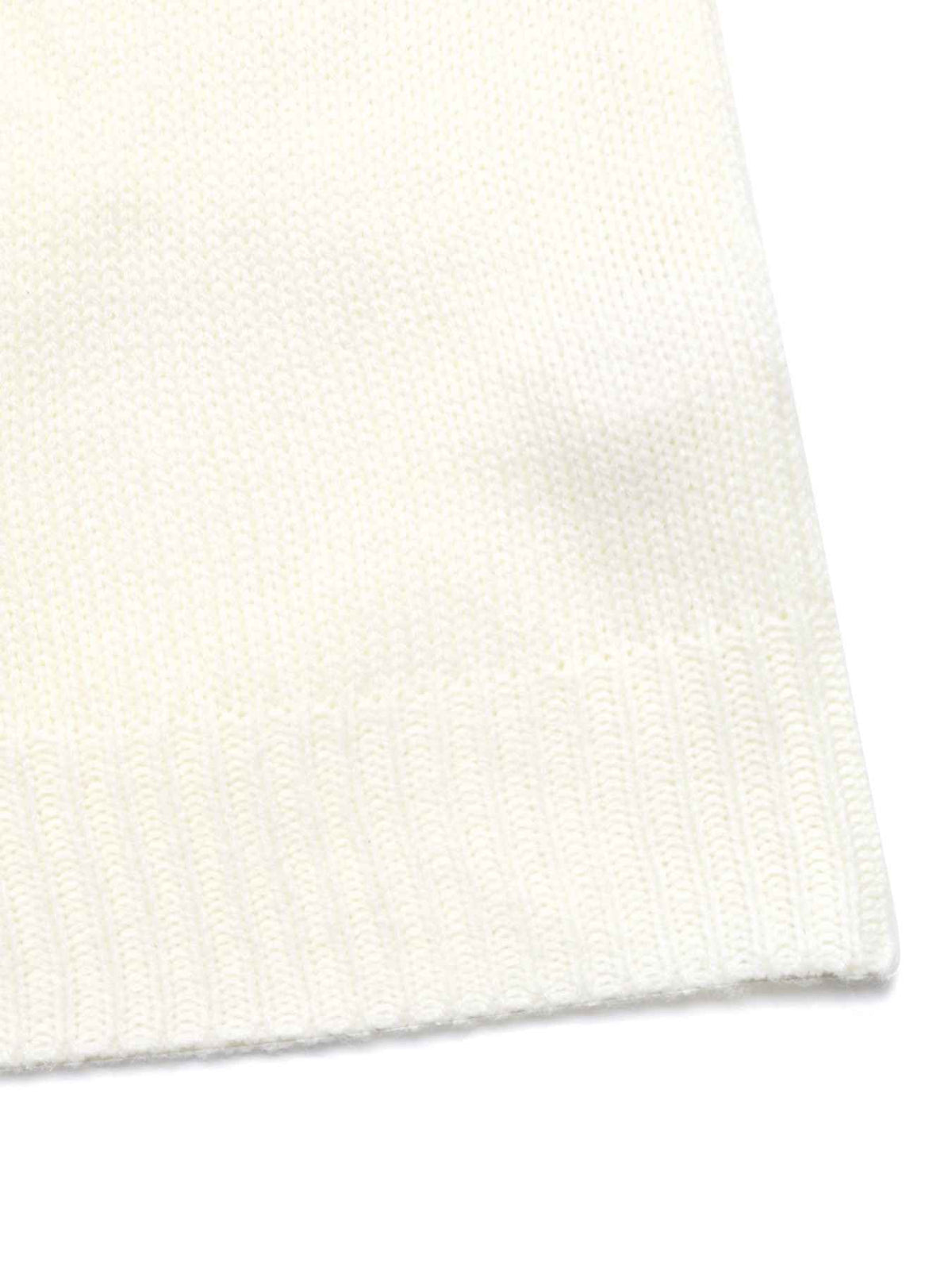 Close-up of a cream-colored knit fabric with a ribbed cuff, showing the fine knit texture against a white background.