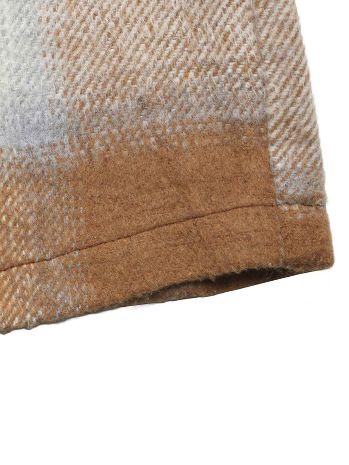 Close-up of a textured woven fabric with a herringbone pattern in beige, brown, and off-white, showing a folded cuff on a plain white background.