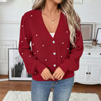 Person wearing a red cardigan with white buttons in a room setting.