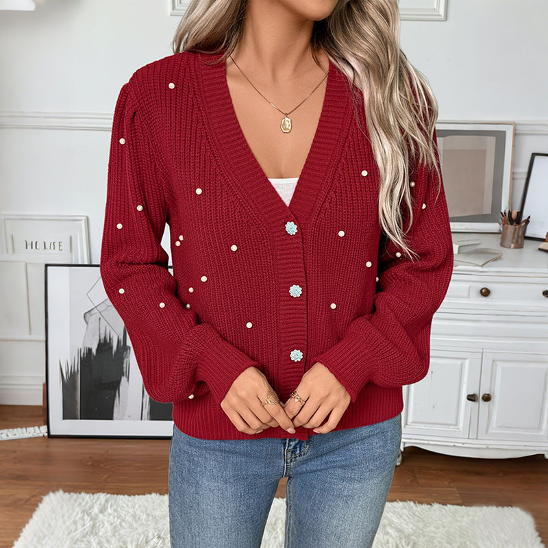 Person wearing a red cardigan with white buttons in a room setting.