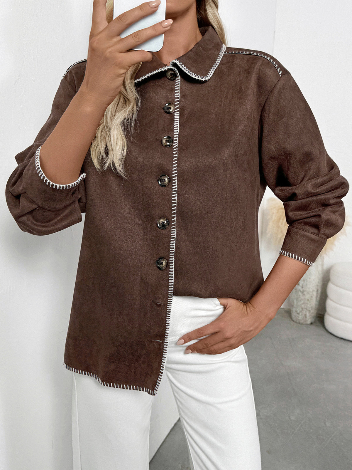Brown jacket with decorative trim worn by a person against a neutral background
