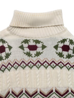 Close-up of a cream-colored sweater with green and red pattern on a white background