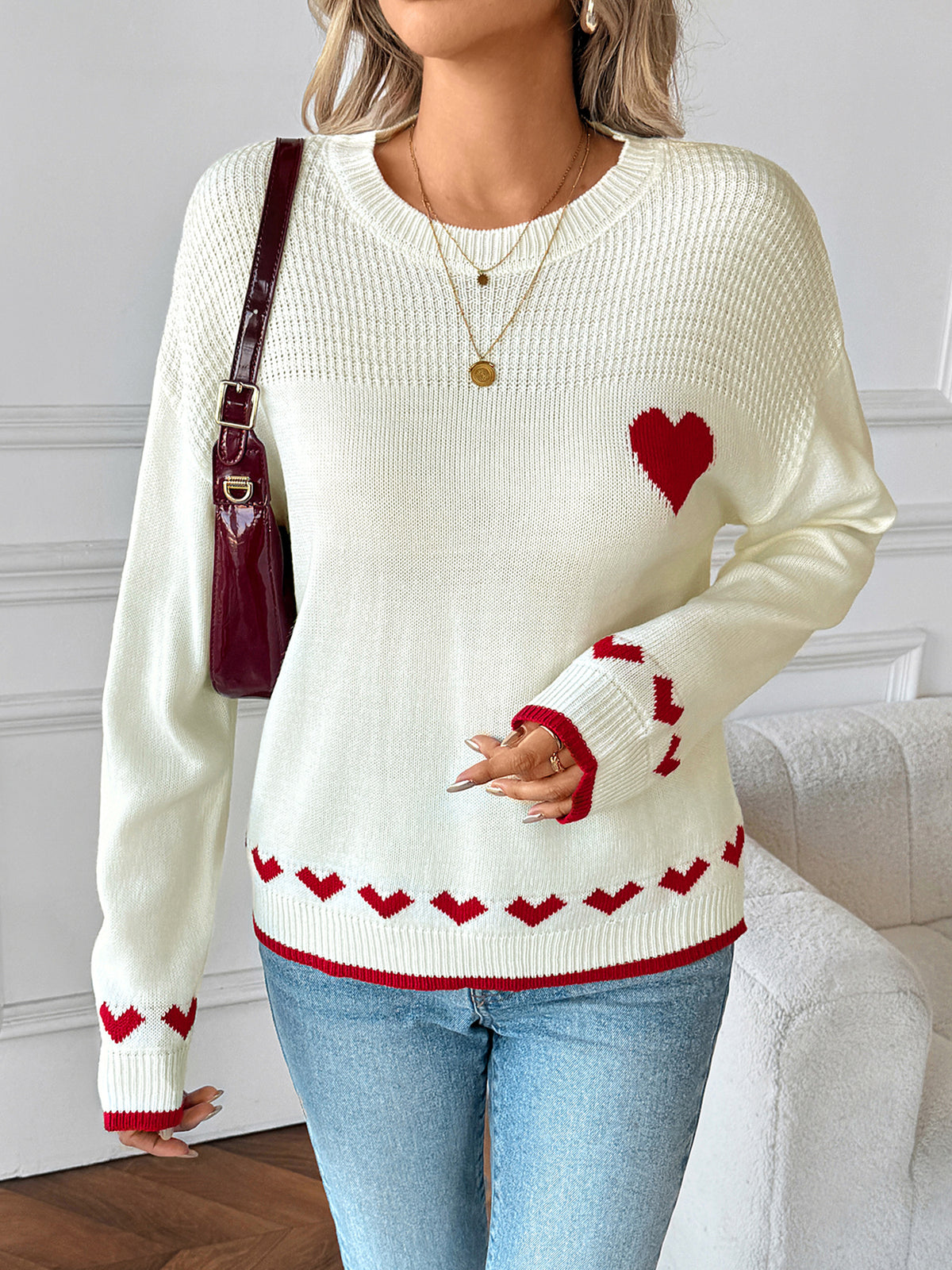 Woman wearing a white sweater with red heart designs in a living room setting