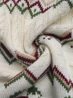 Close-up of a knitted fabric with a pattern featuring white, green, and red colors.